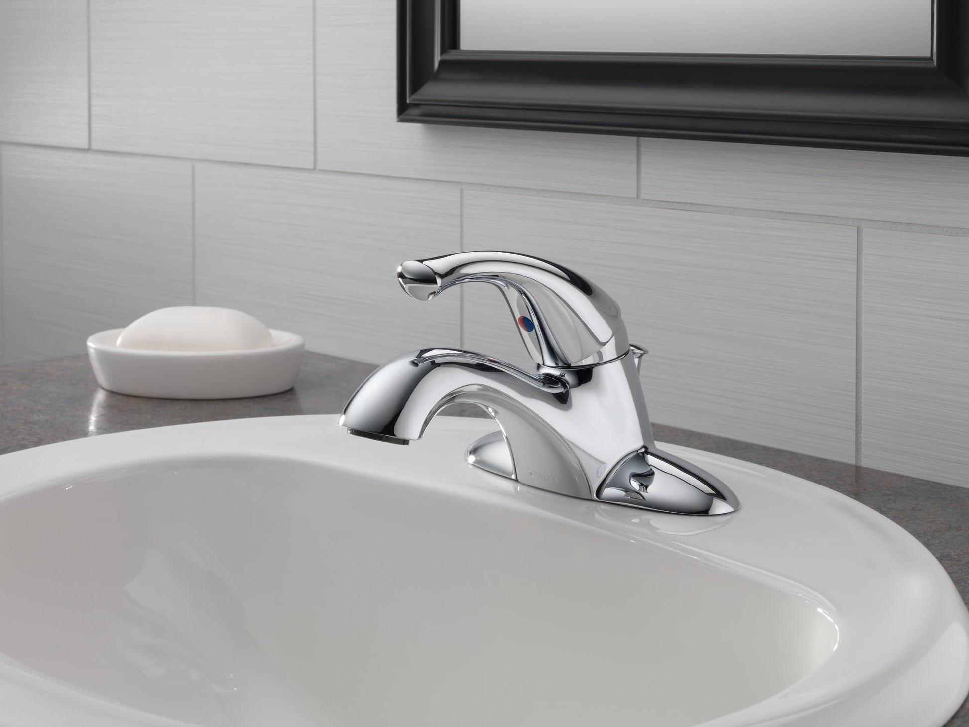 Chrome single-handle bathroom faucet with curved spout mounted on white sink with subway tile backsplash.