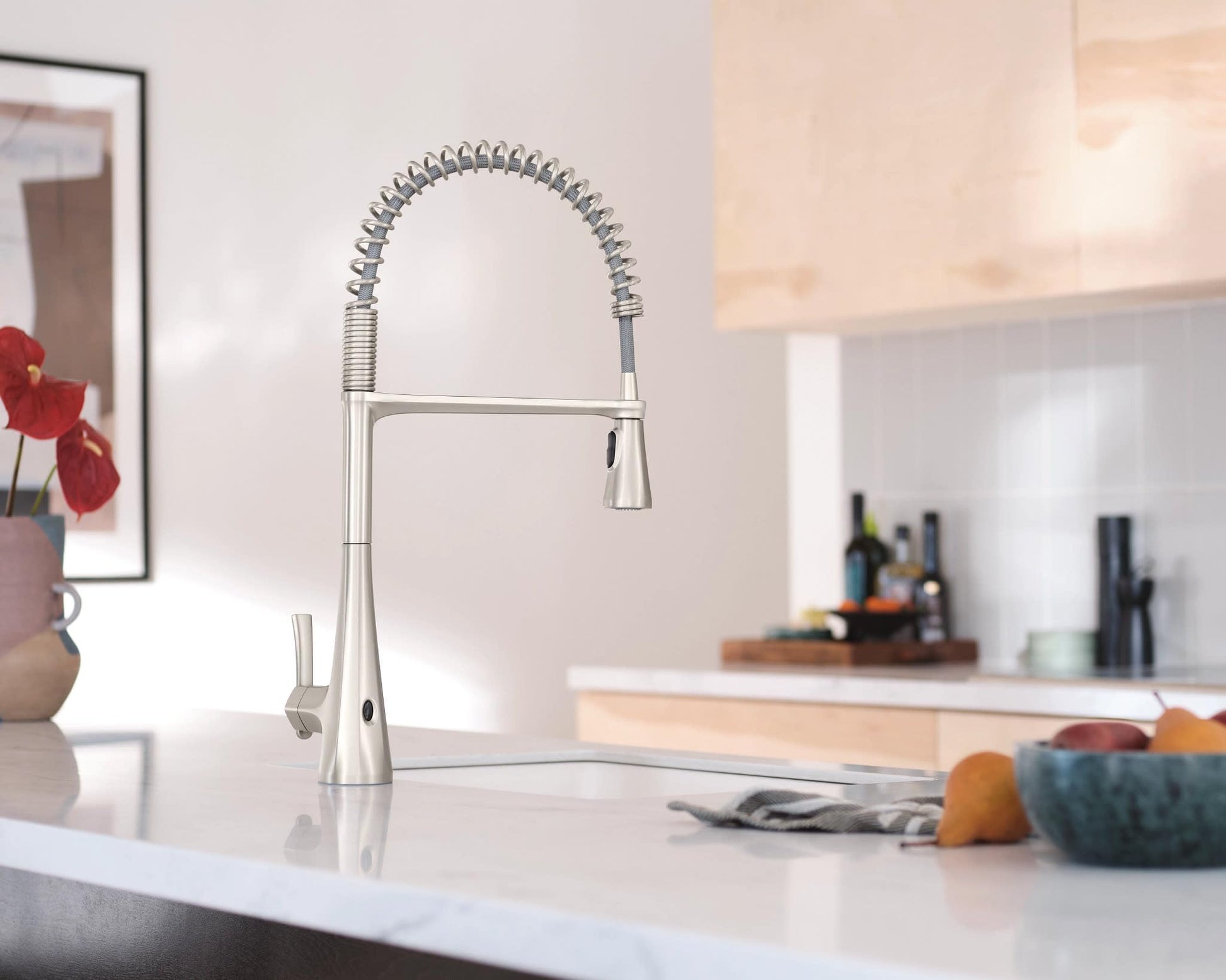 Stainless steel kitchen faucet with high arc spout, coiled pulldown sprayer hose, and sensor activation.