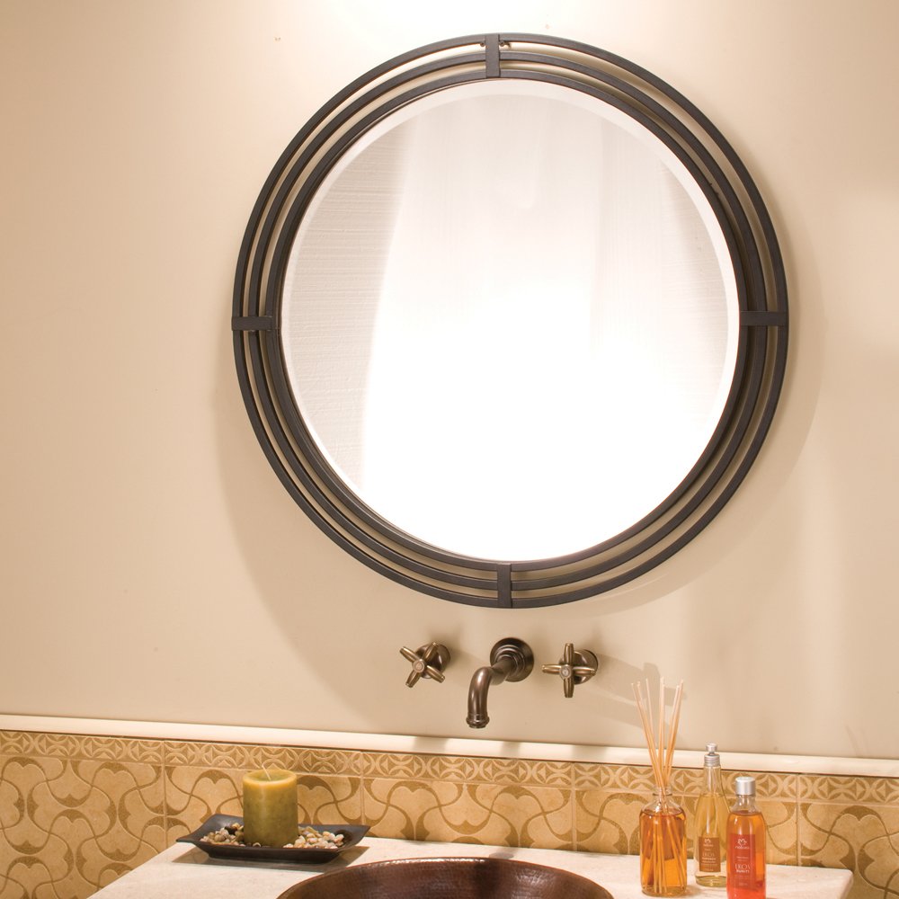 Circular wall mirror with multi-band metal frame in bronze finish above bathroom sink with wall-mounted faucet.