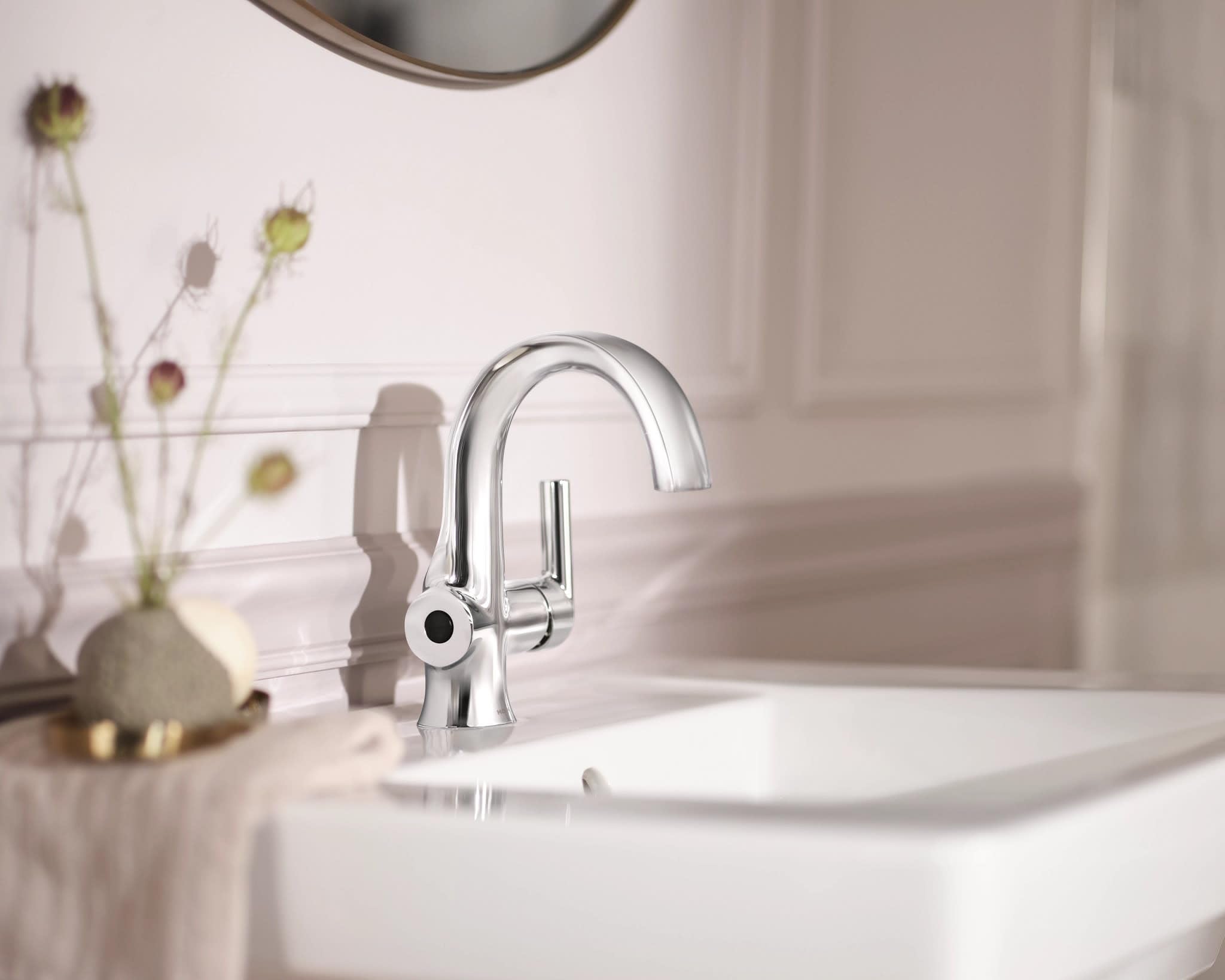 Chrome single-handle bathroom sink faucet with curved spout mounted on white sink countertop.
