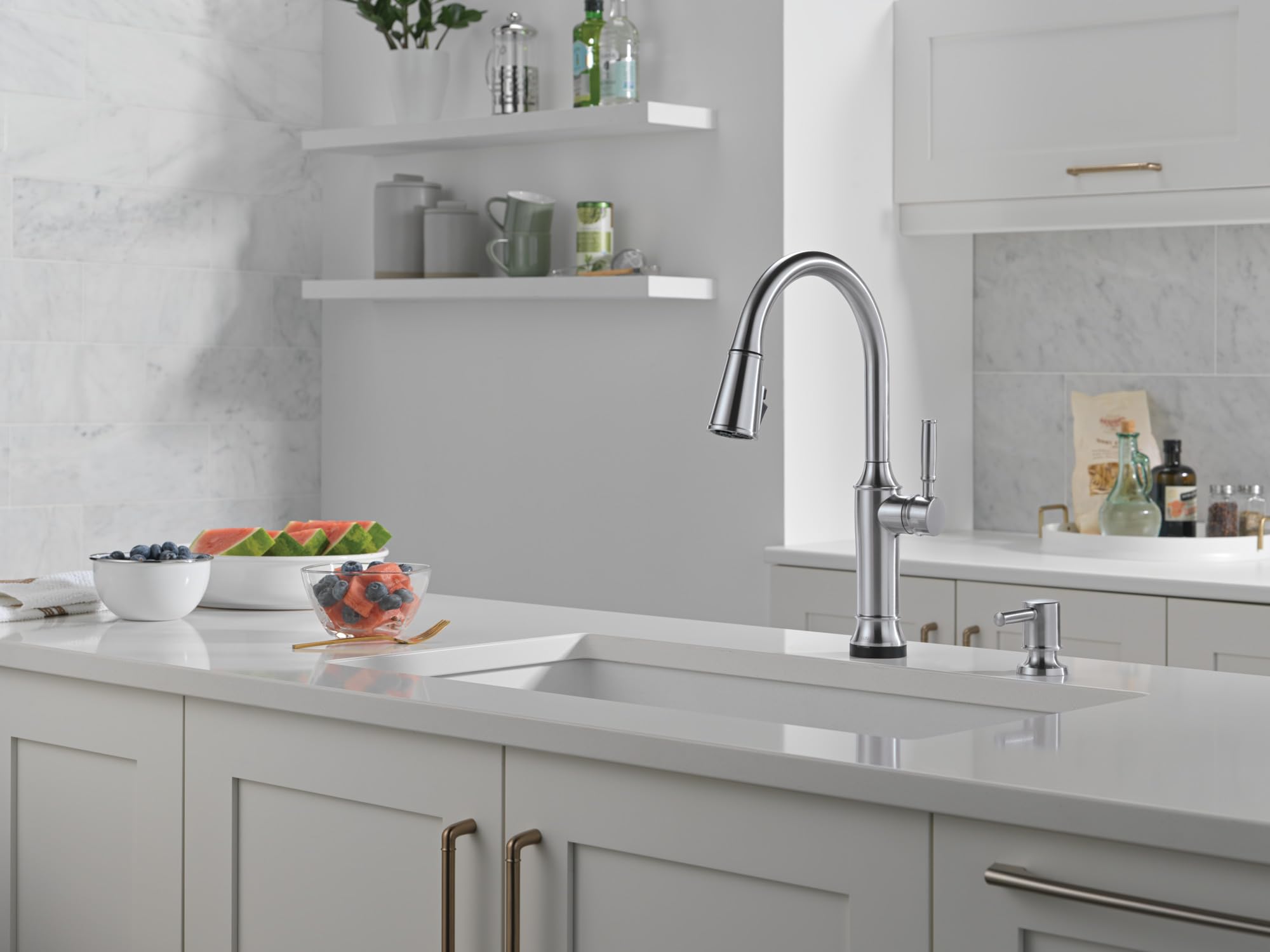 Stainless steel soap dispenser with cylindrical pump head on kitchen sink counter.