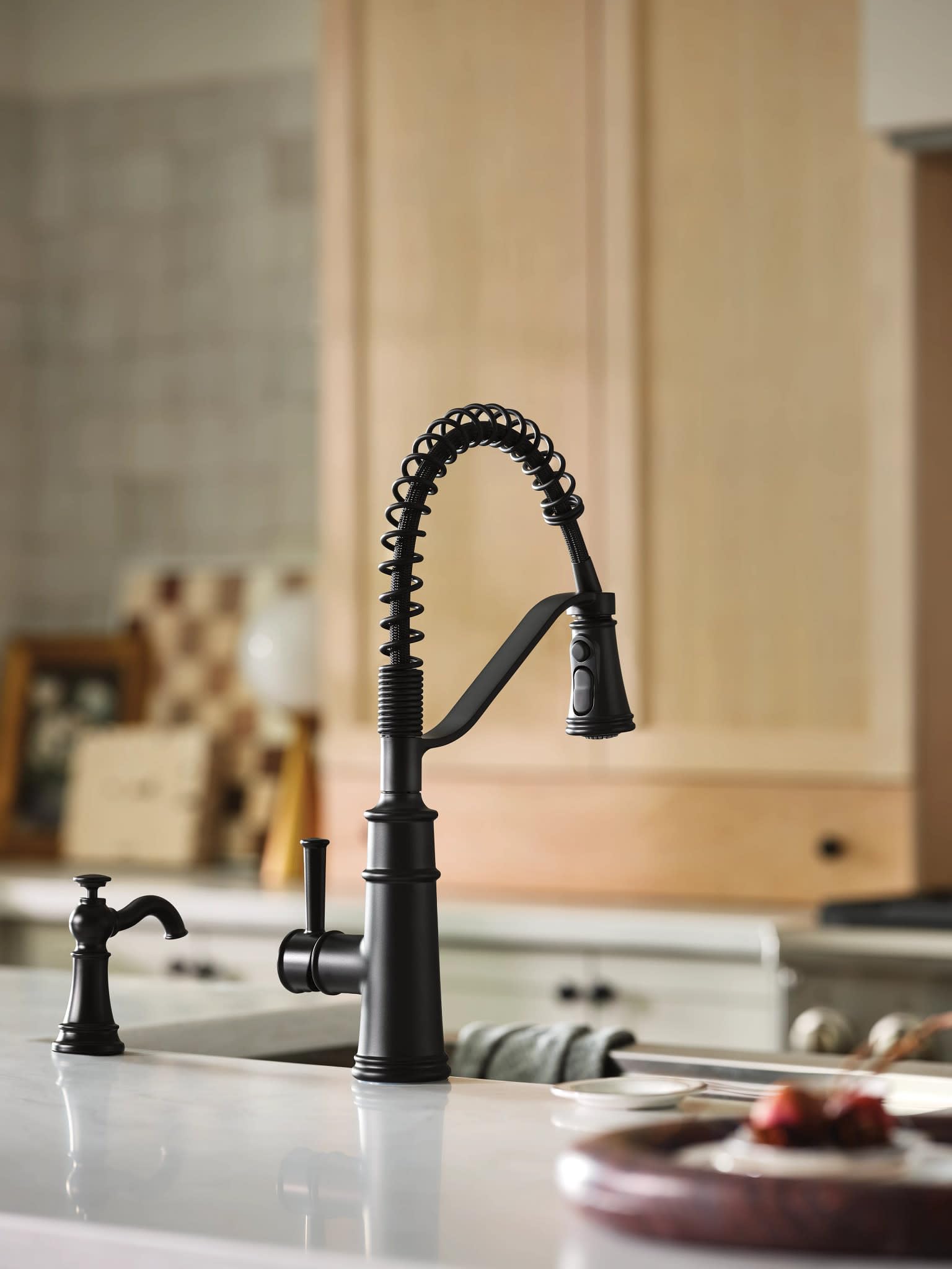 Matte black kitchen faucet with coiled spring spout and single handle control mounted on white countertop.