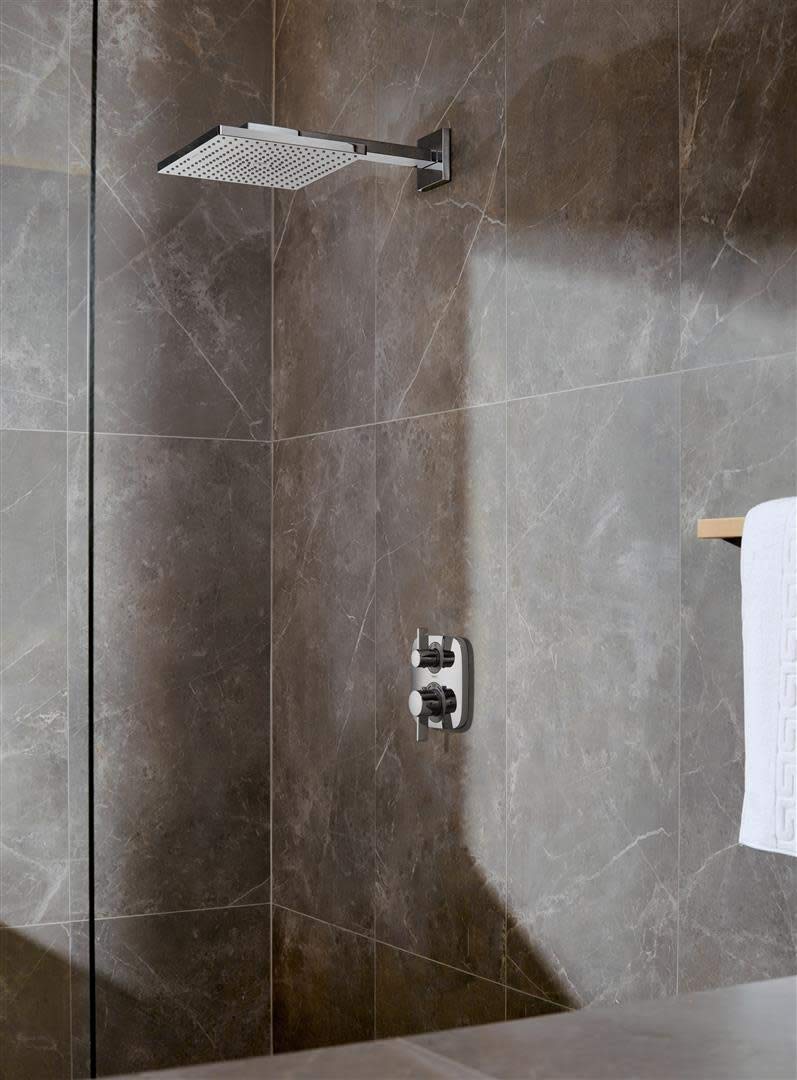 Brushed nickel thermostatic shower trim with square overhead rain showerhead and dual control handles mounted on marble tile 