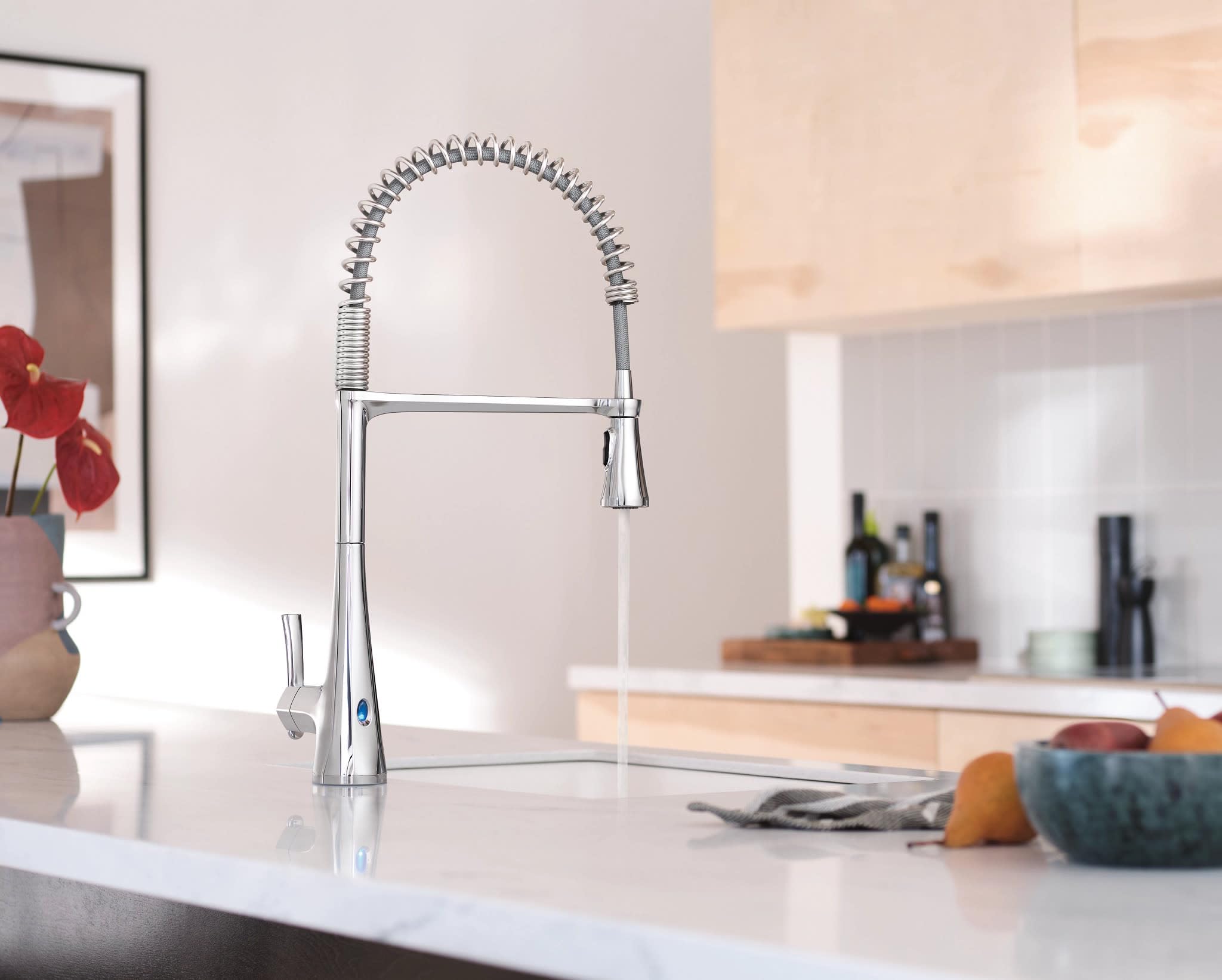 Chrome high-arc kitchen faucet with coiled pulldown sprayer head and motion sensor controls mounted on white countertop.