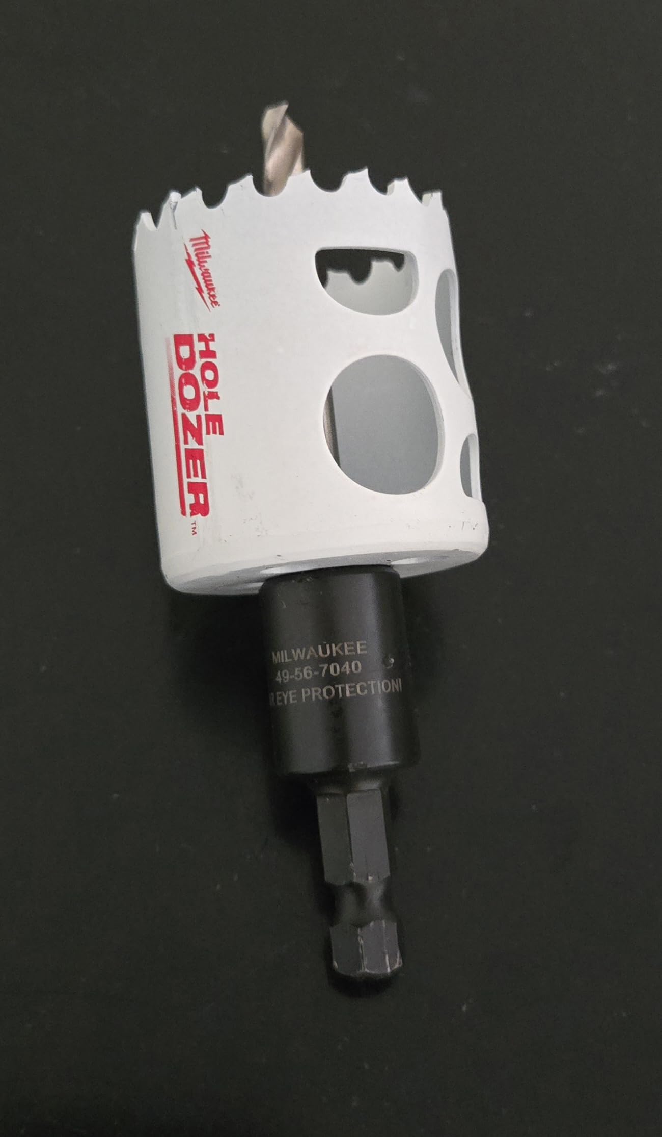 White bi-metal hole saw with jagged cutting edge and black arbor shaft attached below.