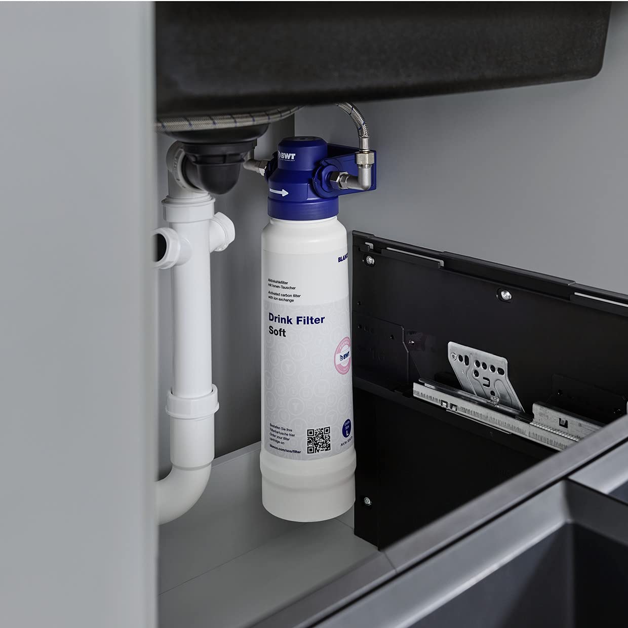 White cylindrical filter cartridge labeled "Drink Filter Soft" installed under sink with blue head connector and white tubing