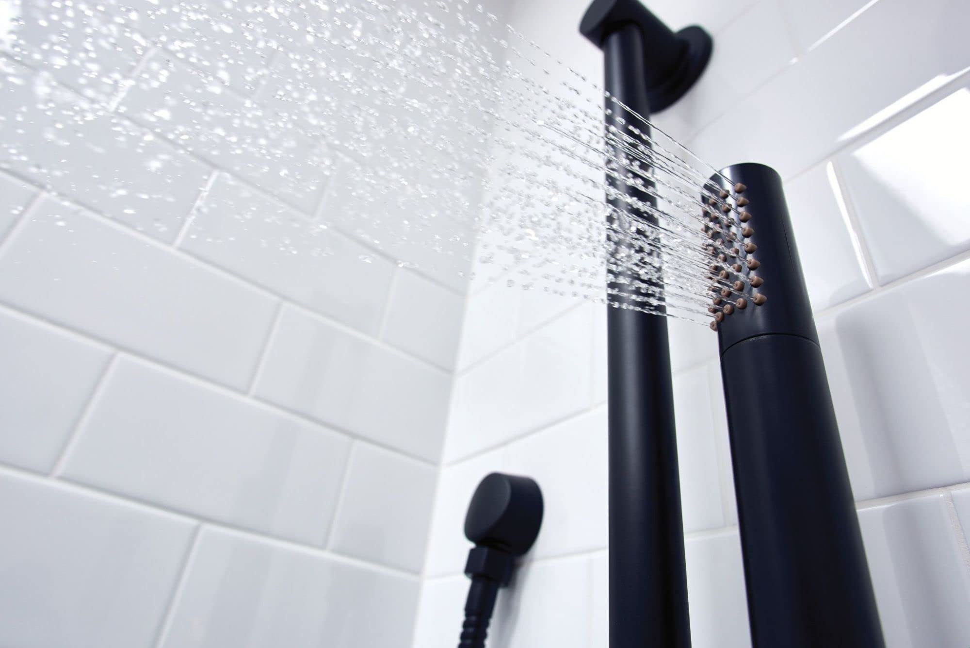 Matte black handheld shower head with adjustable spray pattern mounted on slide bar above white subway tile wall.