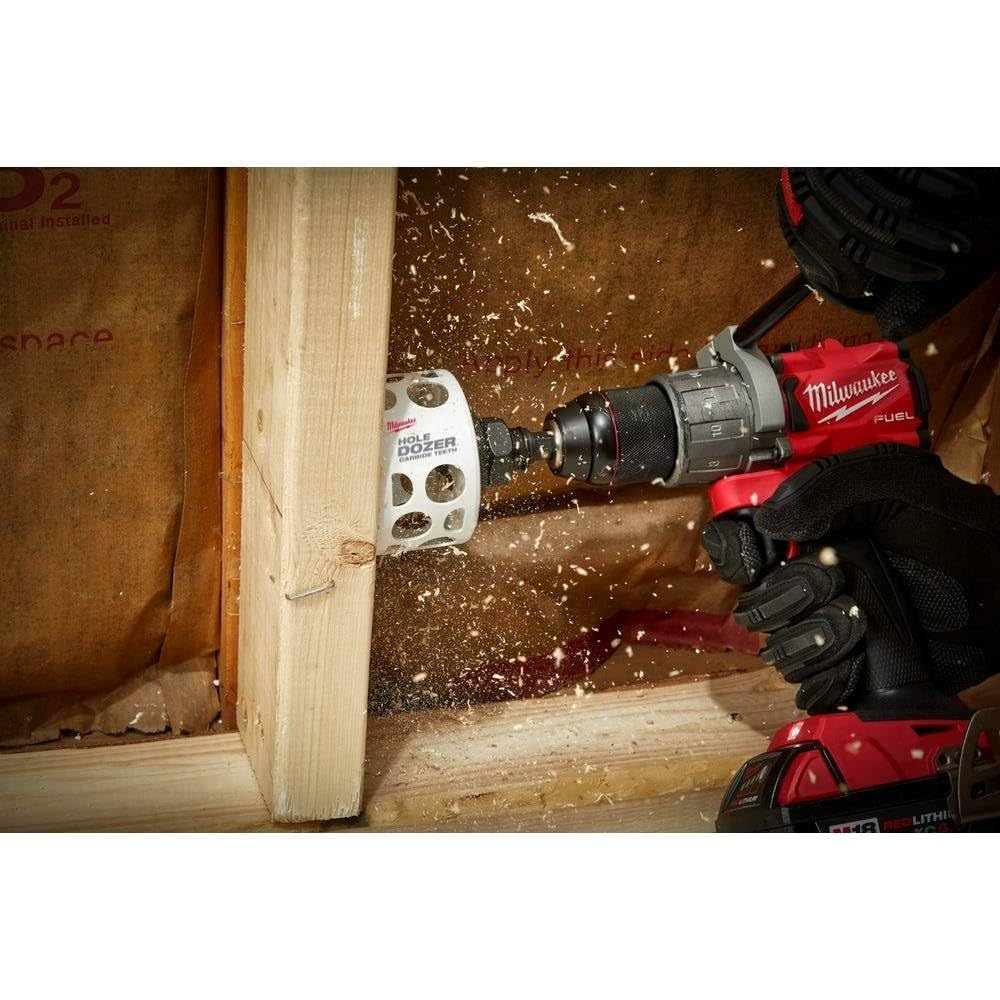 Milwaukee HOLE DOZER hole saw with carbide teeth attached to red drill boring into wood framing.