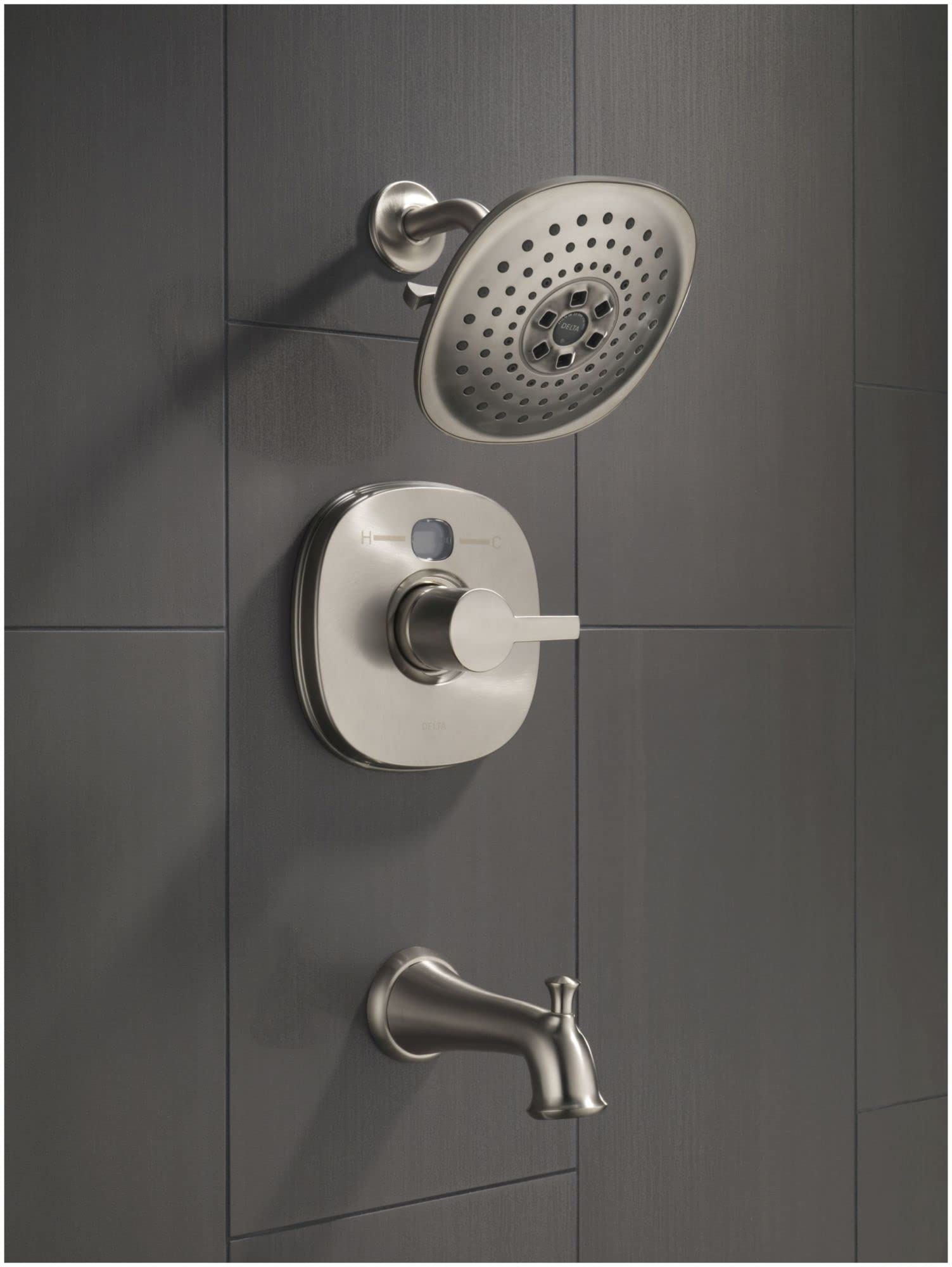 Black stainless steel shower system with perforated showerhead, control valve, and tub spout mounted on tiled wall.