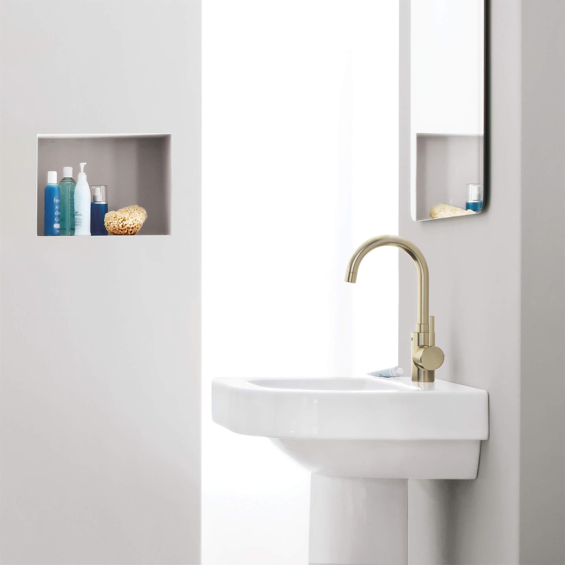 Brushed nickel single-handle bathroom faucet with curved spout mounted on white pedestal sink.