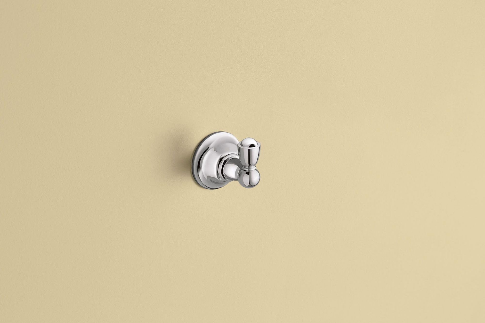 Chrome wall-mount robe hook with circular backplate and dual hooks on beige background.
