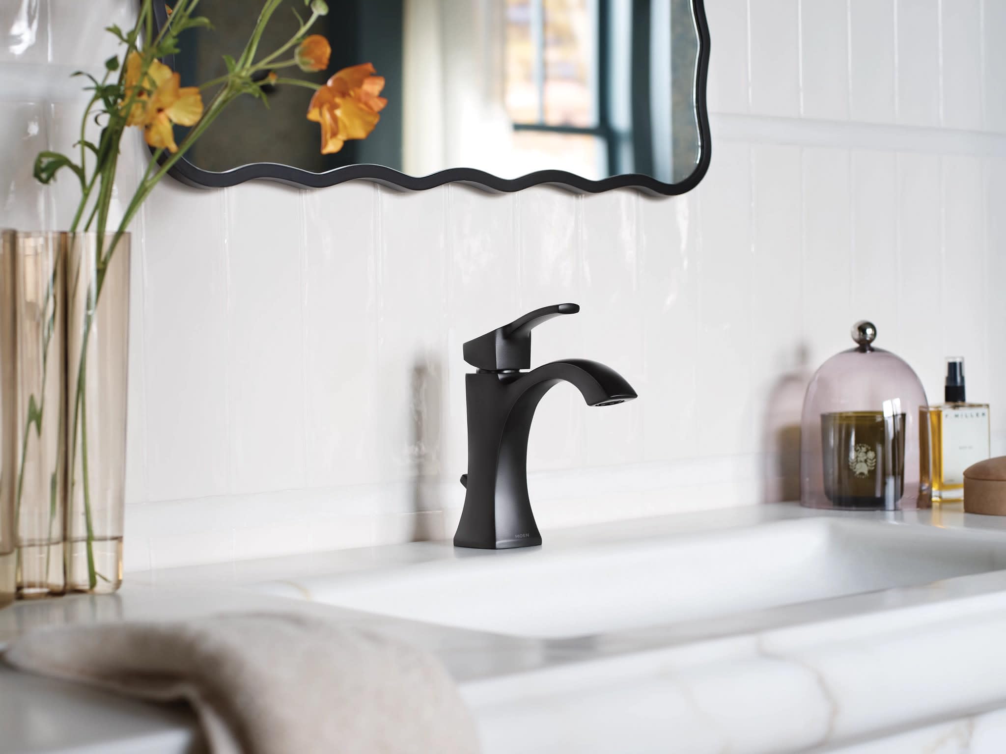 Matte black single-handle bathroom faucet with curved spout installed on white countertop sink.