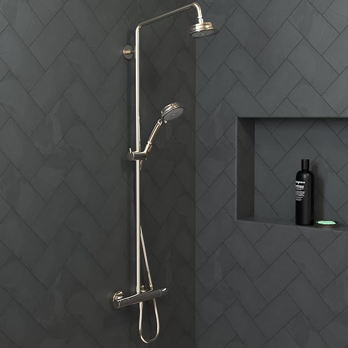 Polished nickel shower system with overhead rainfall head and handheld wand mounted on herringbone tile wall.
