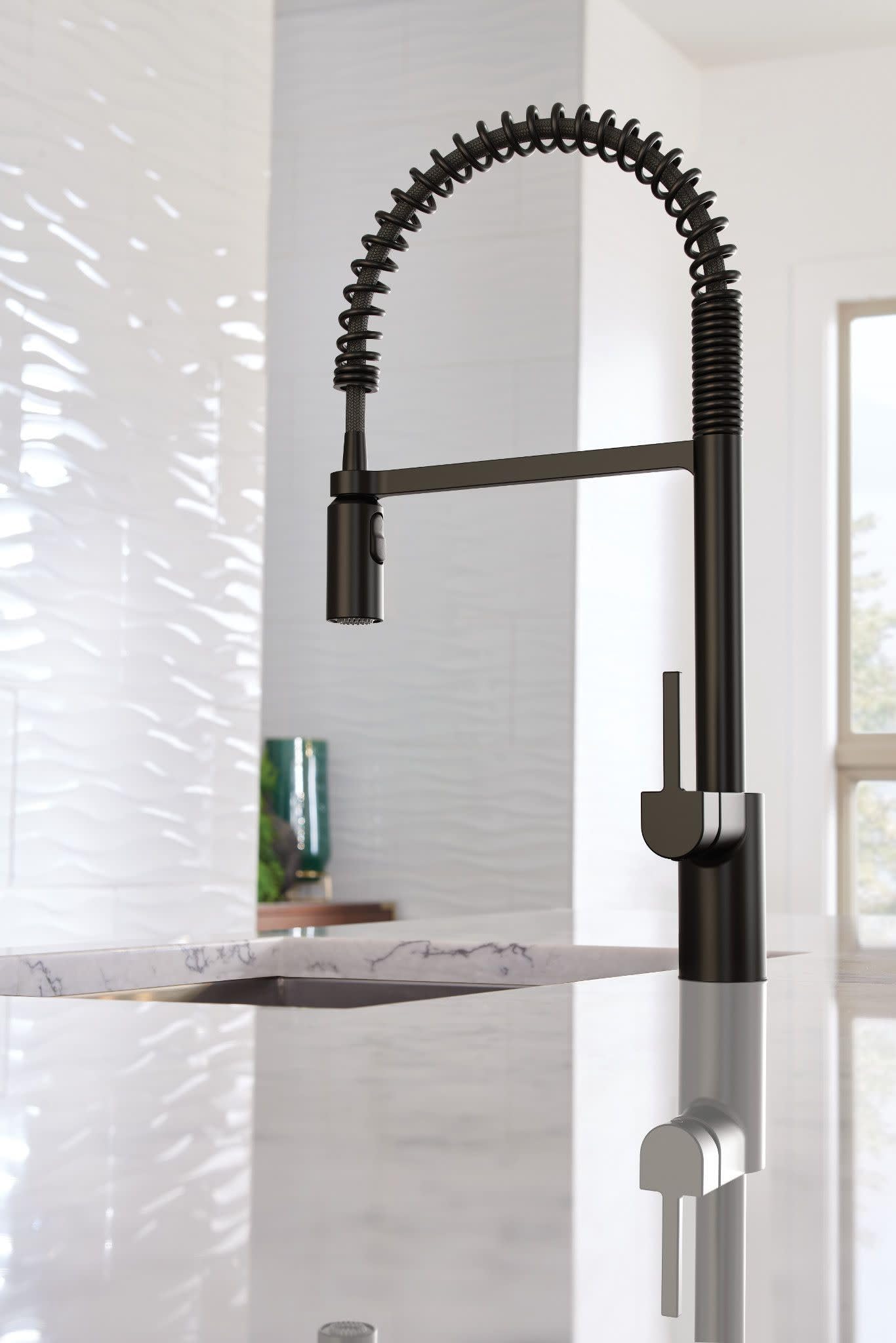 Matte black pulldown kitchen faucet with coiled spring hose and pre-rinse sprayer mounted on marble countertop.