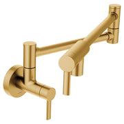 Brushed gold wall-mounted pot filler faucet with double-jointed folding swing arm and lever handle.