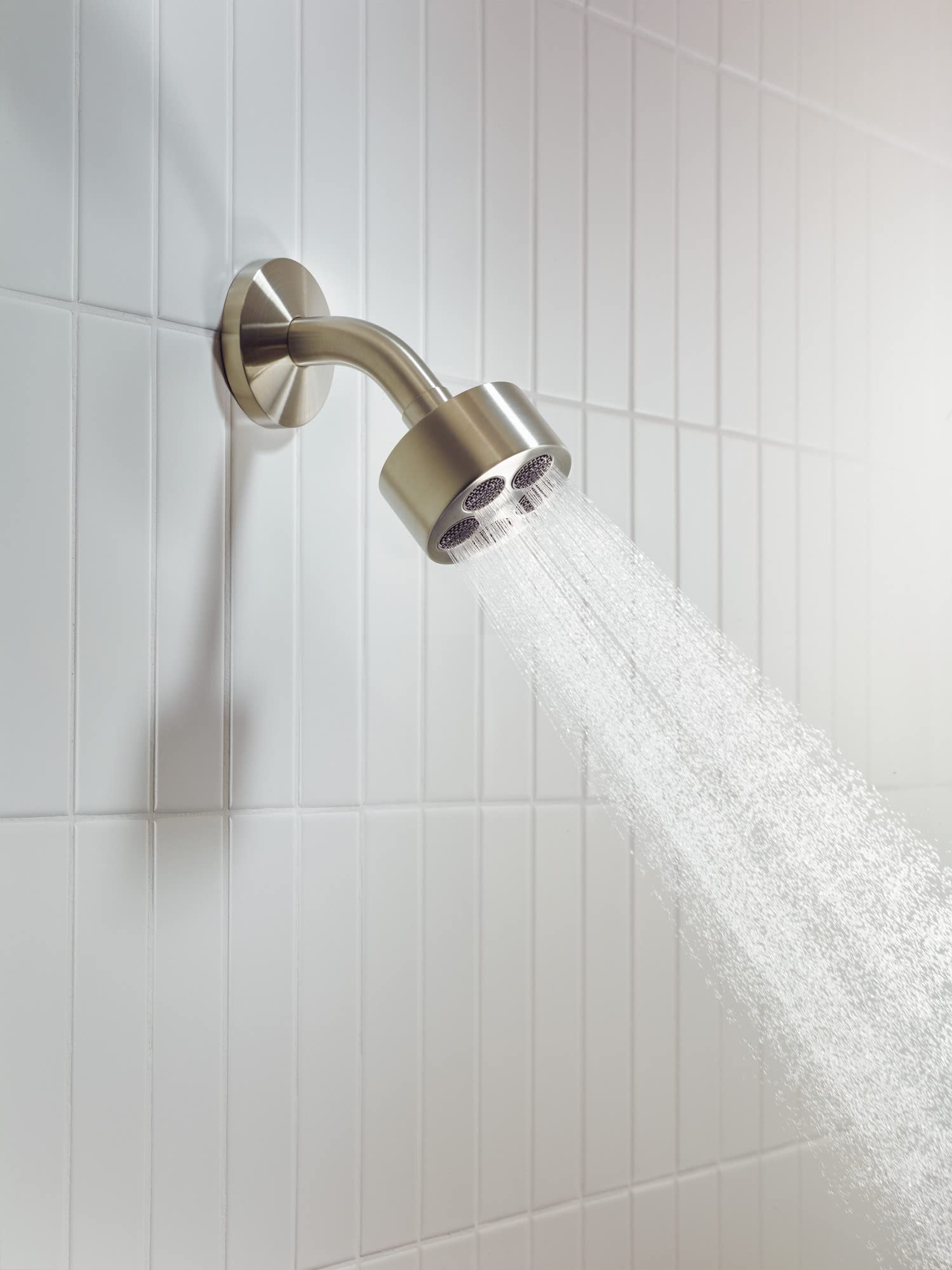 Brushed nickel single-jet shower head mounted on wall tile with water spray visible.
