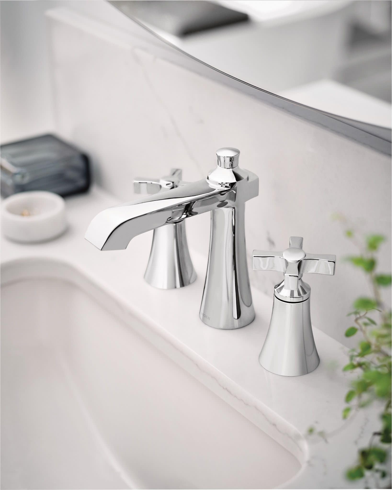 Chrome widespread bathroom faucet with curved spout and two cross handles mounted on white sink.