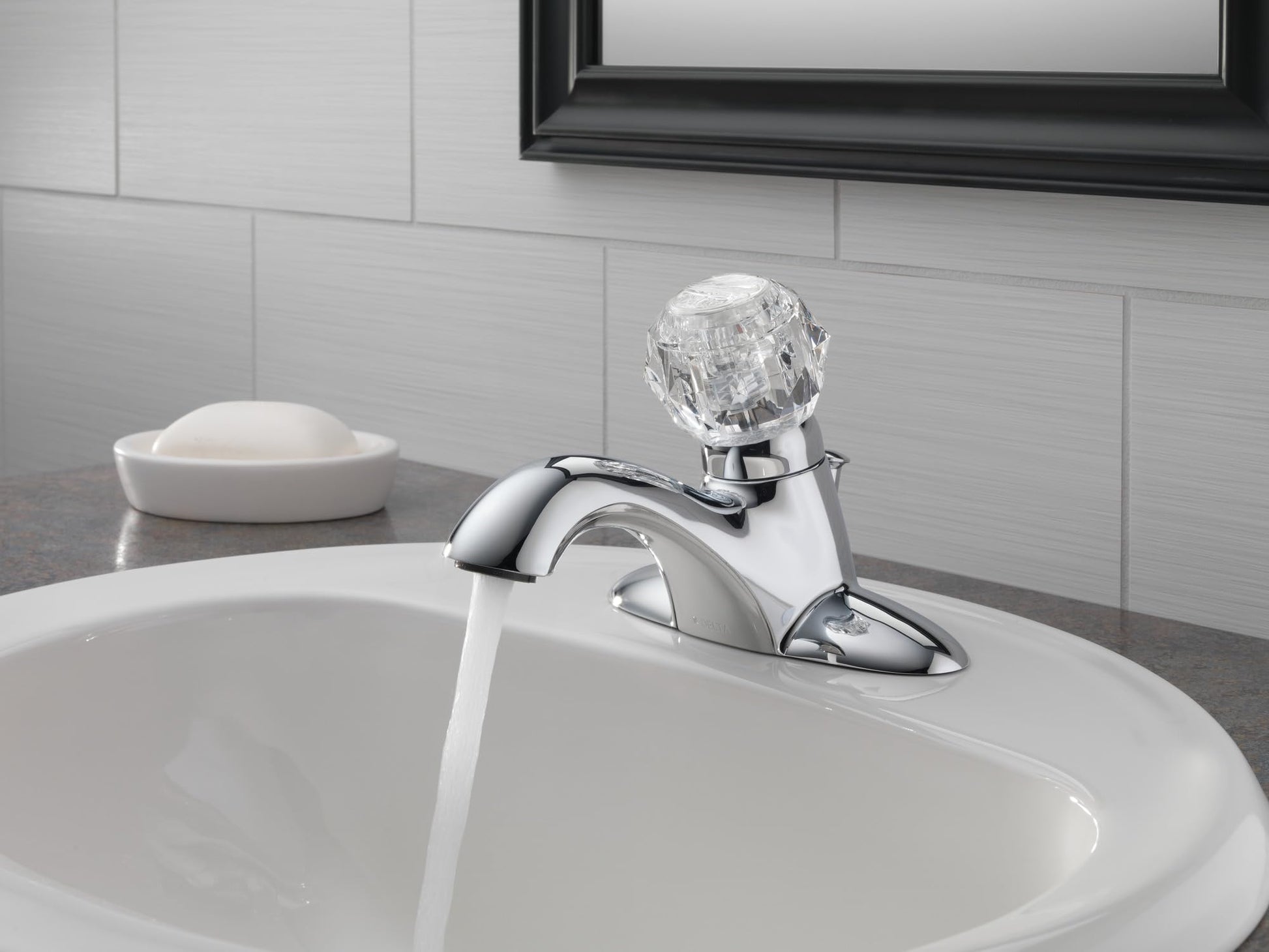 Chrome single-handle bathroom faucet with curved spout and crystal knob installed on white sink.