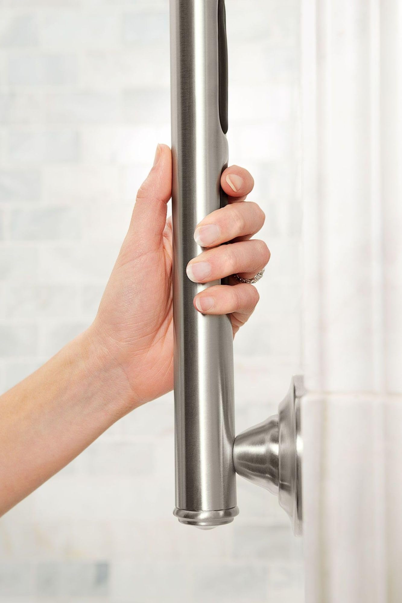 Stainless steel cylindrical grab bar with brushed finish mounted to wall, shown being gripped by a hand.