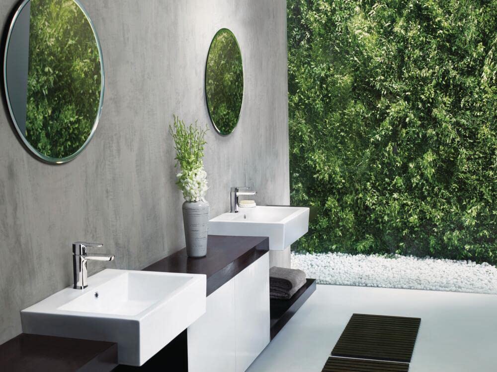 Chrome single-handle bathroom faucet mounted on white rectangular sink in modern spa-style bathroom.