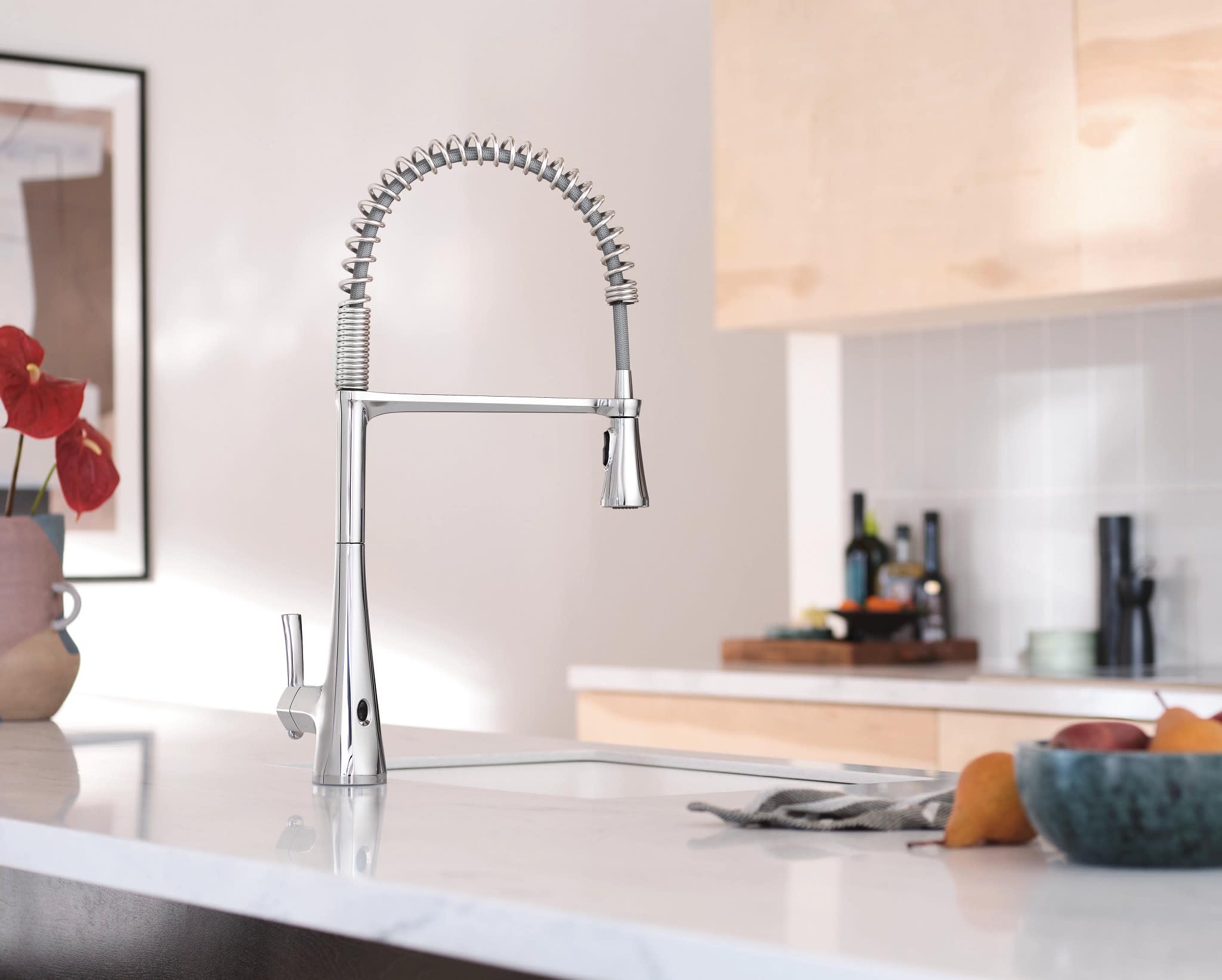 Chrome kitchen faucet with high arc spout, coiled pull-down sprayer, and single handle mounted on white countertop.