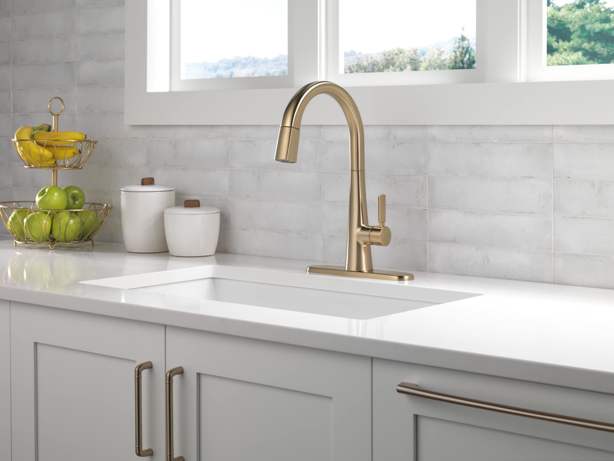 Champagne bronze single-handle kitchen faucet with high arched spout mounted on white countertop with sink.