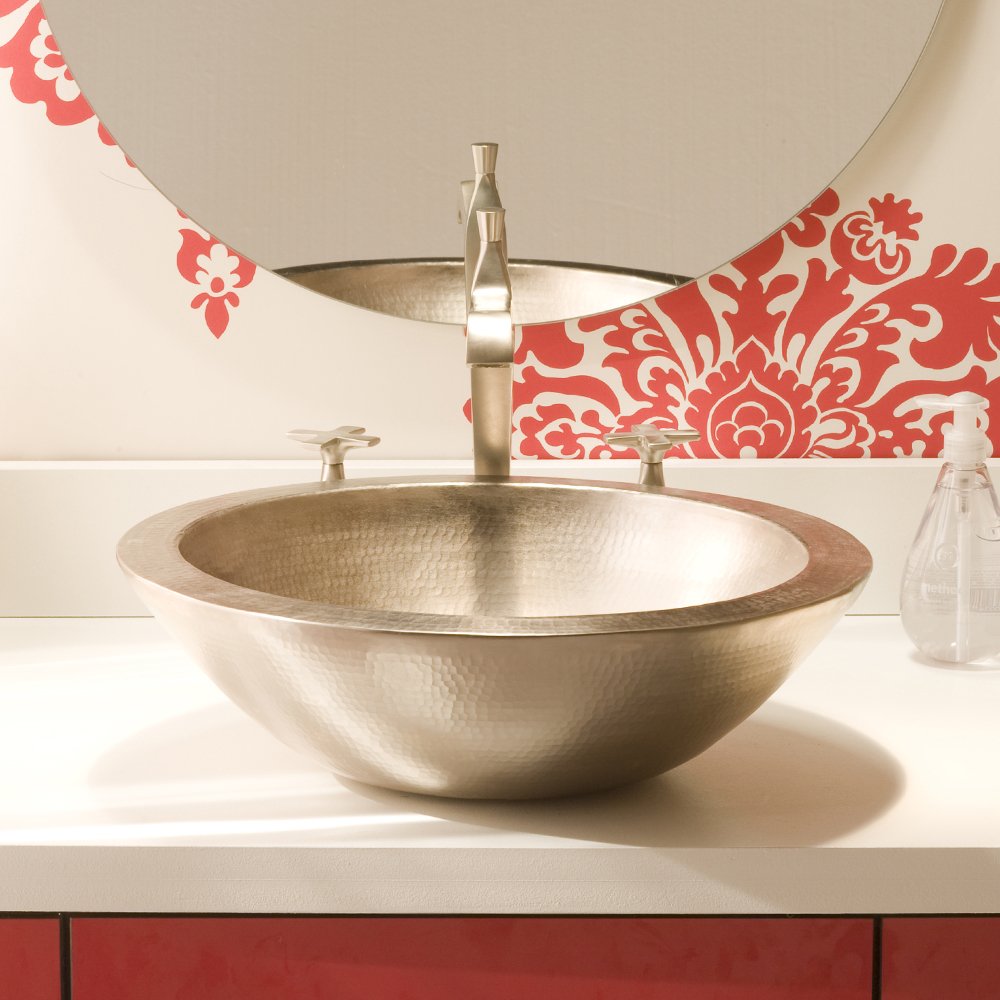 Hammered copper vessel sink with brushed nickel faucet mounted on white bathroom countertop.