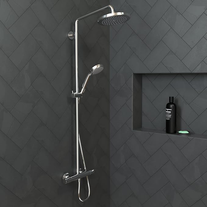 Chrome shower system with overhead rainfall head and handheld wand mounted on dark herringbone tile wall.