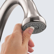Chrome prep faucet with curved spout and multi-spray showerhead held in hand.