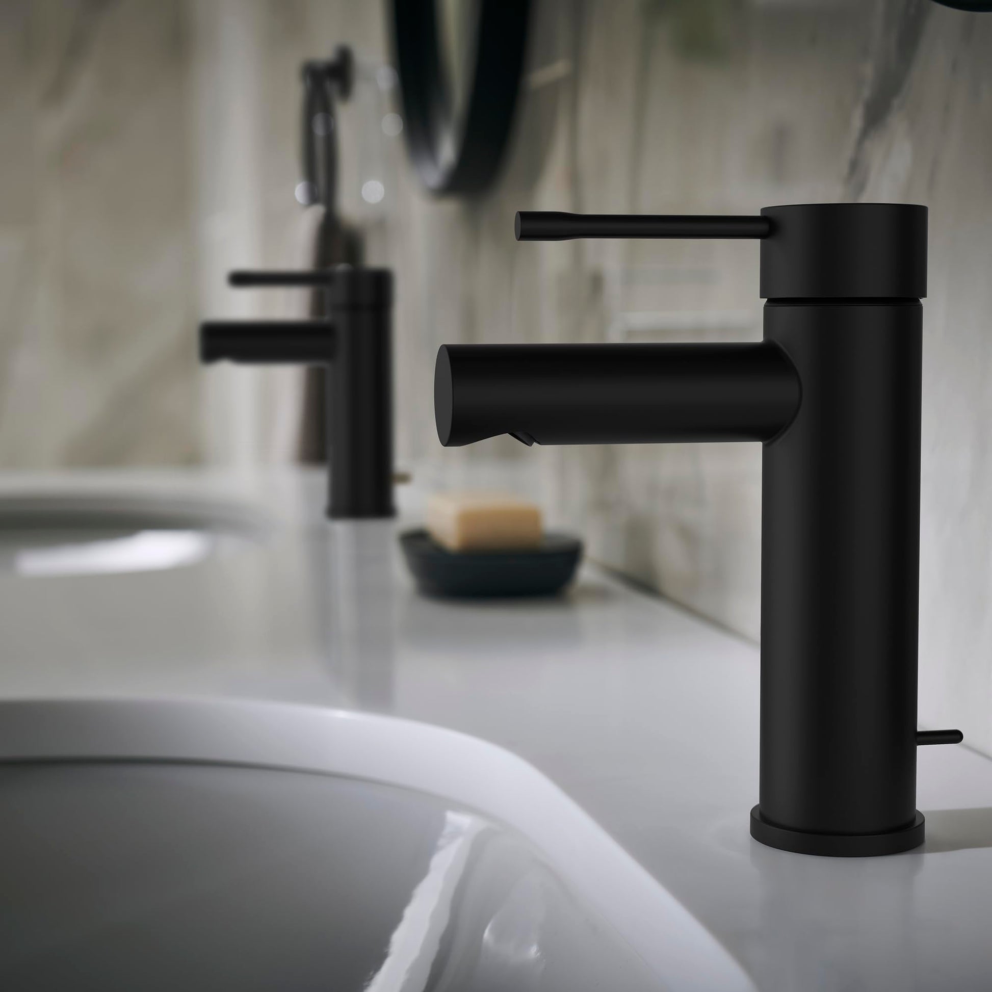 Matte black single-handle bathroom faucet with cylindrical spout positioned above white sink basin.