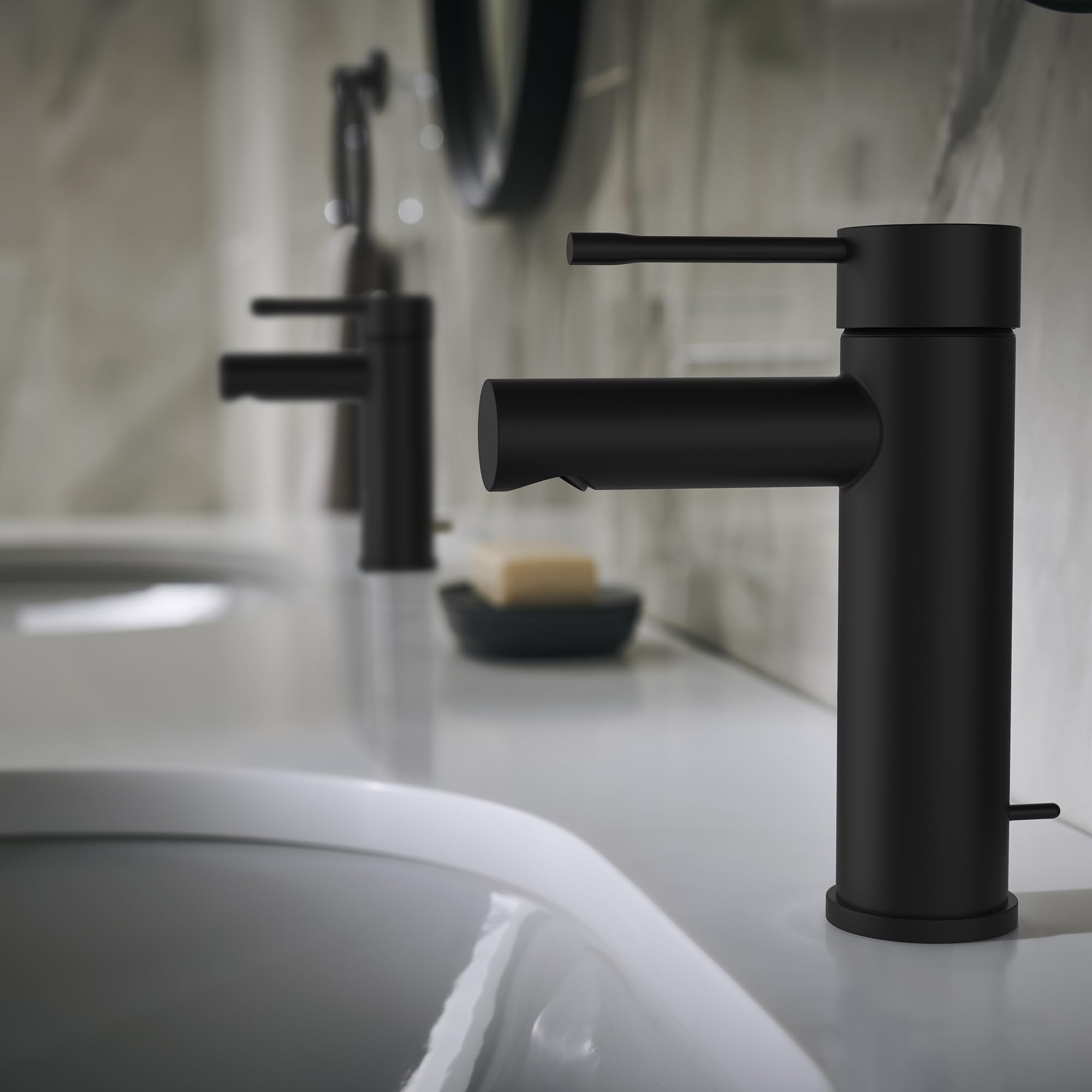 Matte black single-handle bathroom faucet with cylindrical spout positioned above white sink basin.