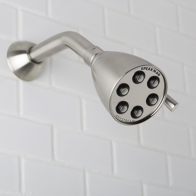Brushed nickel shower head with circular face featuring seven spray jets and adjustable arm mounted on white tile wall.