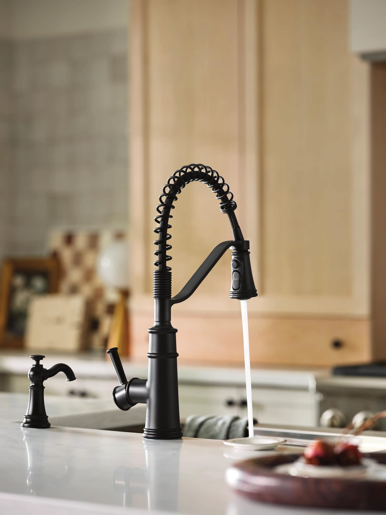 Matte black kitchen faucet with coiled spring spout, single handle, and pre-rinse spray head mounted on countertop.