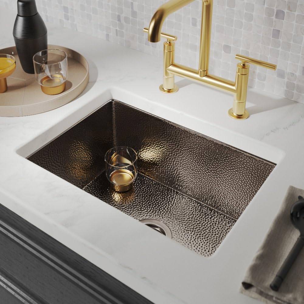 Antique copper undermount kitchen sink with hammered interior finish installed in white countertop.