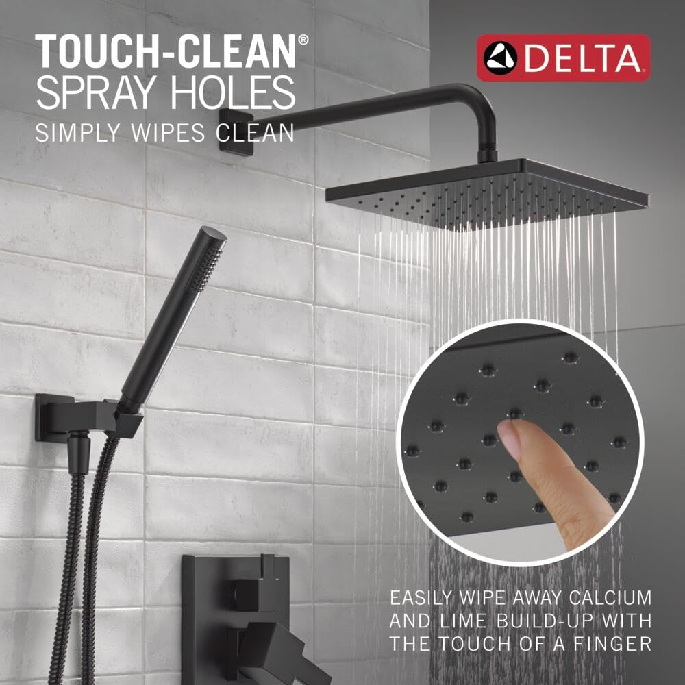 Matte black Delta shower system with square raincan head, curved arm, hand shower, and control valve mounted on white tile wa