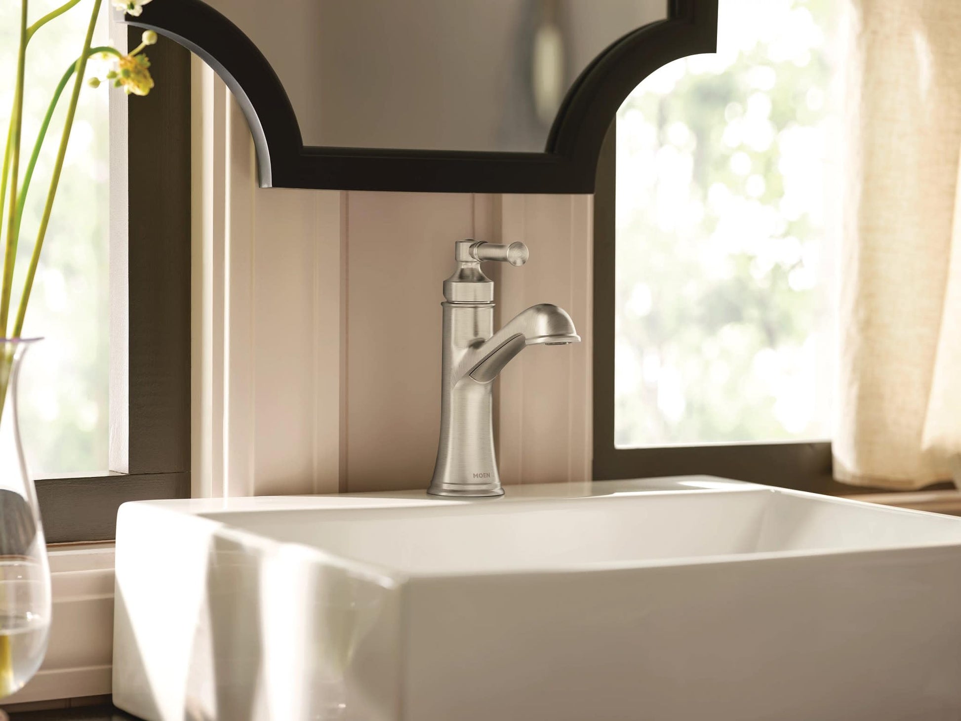 Brushed nickel single-handle bathroom sink faucet with curved spout mounted on white vessel sink.