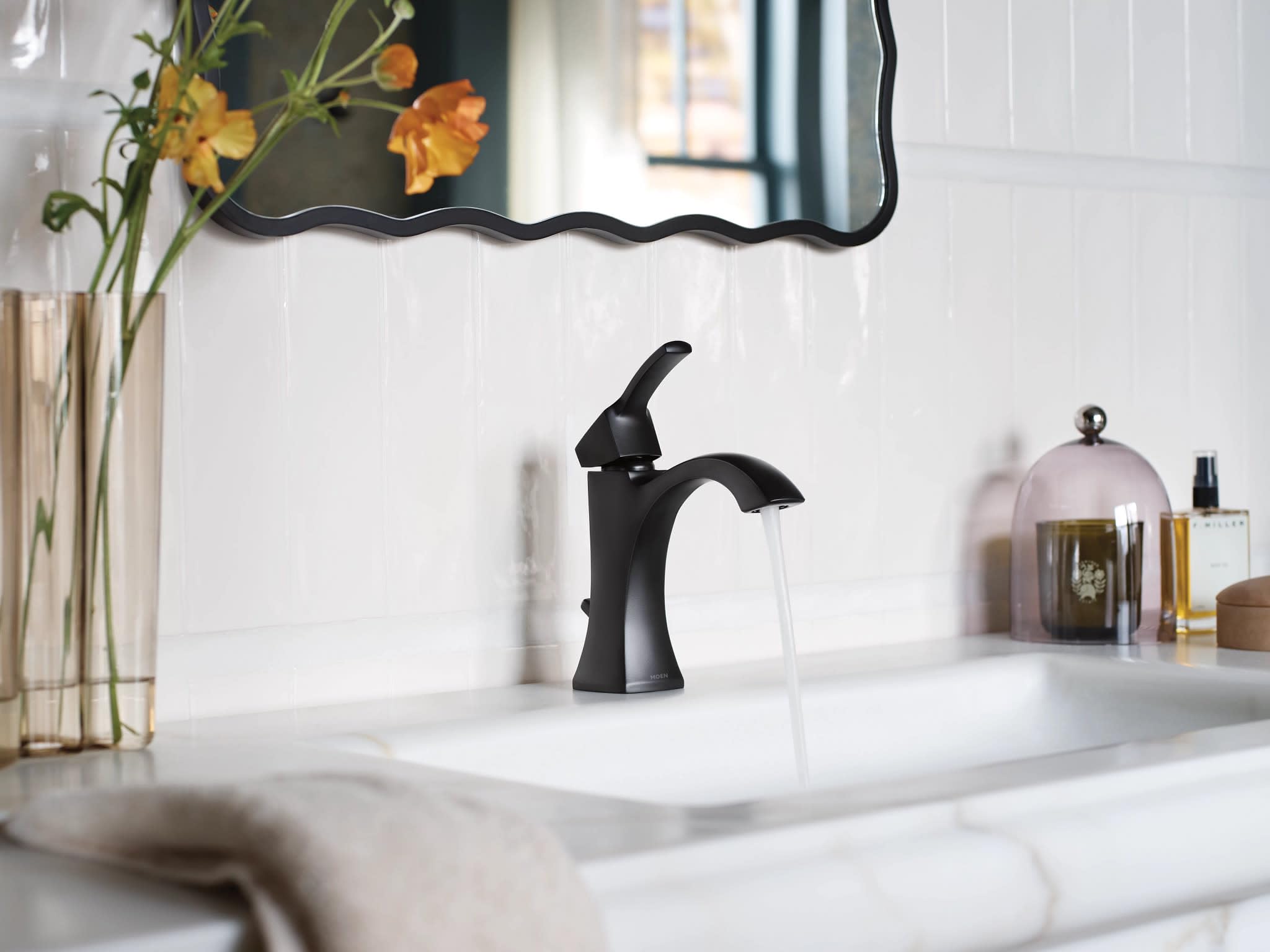 Matte black single-handle bathroom faucet with curved spout installed on white sink counter.