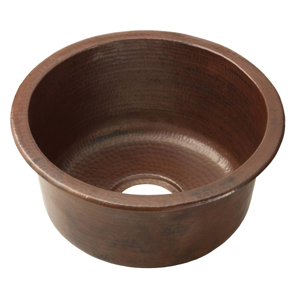Hammered copper round bar sink with dark patina finish and drain opening.