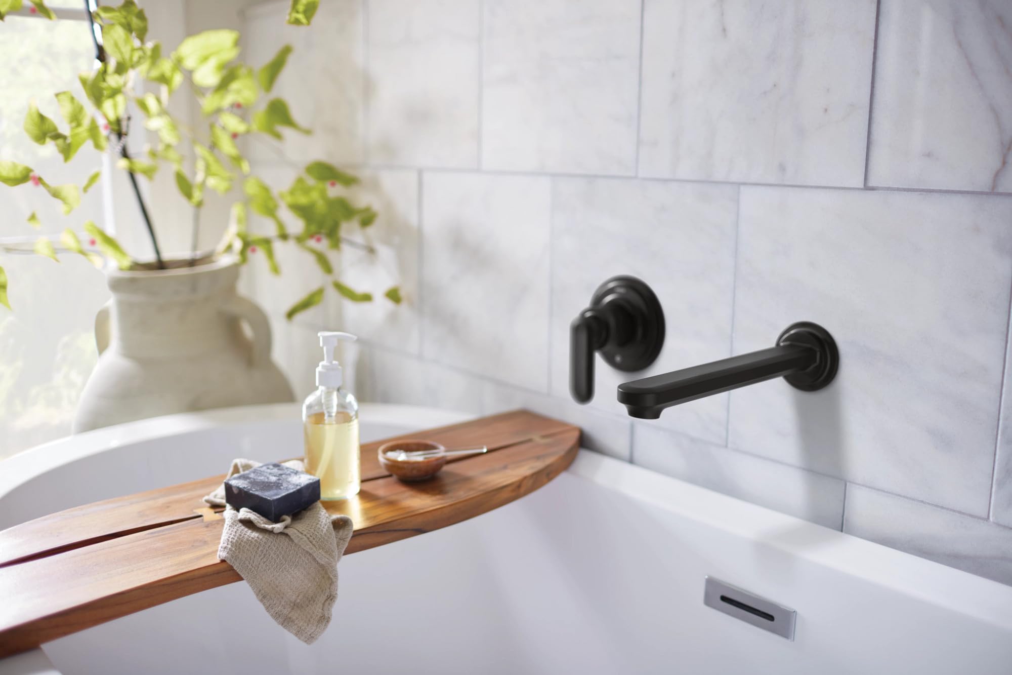 Matte black wall-mounted tub filler with single lever handle installed above white bathtub.