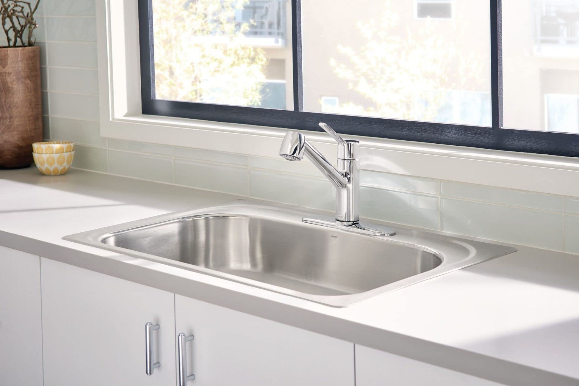 Stainless steel single-handle pullout kitchen faucet with high spray pressure mounted above a rectangular sink in white cabin