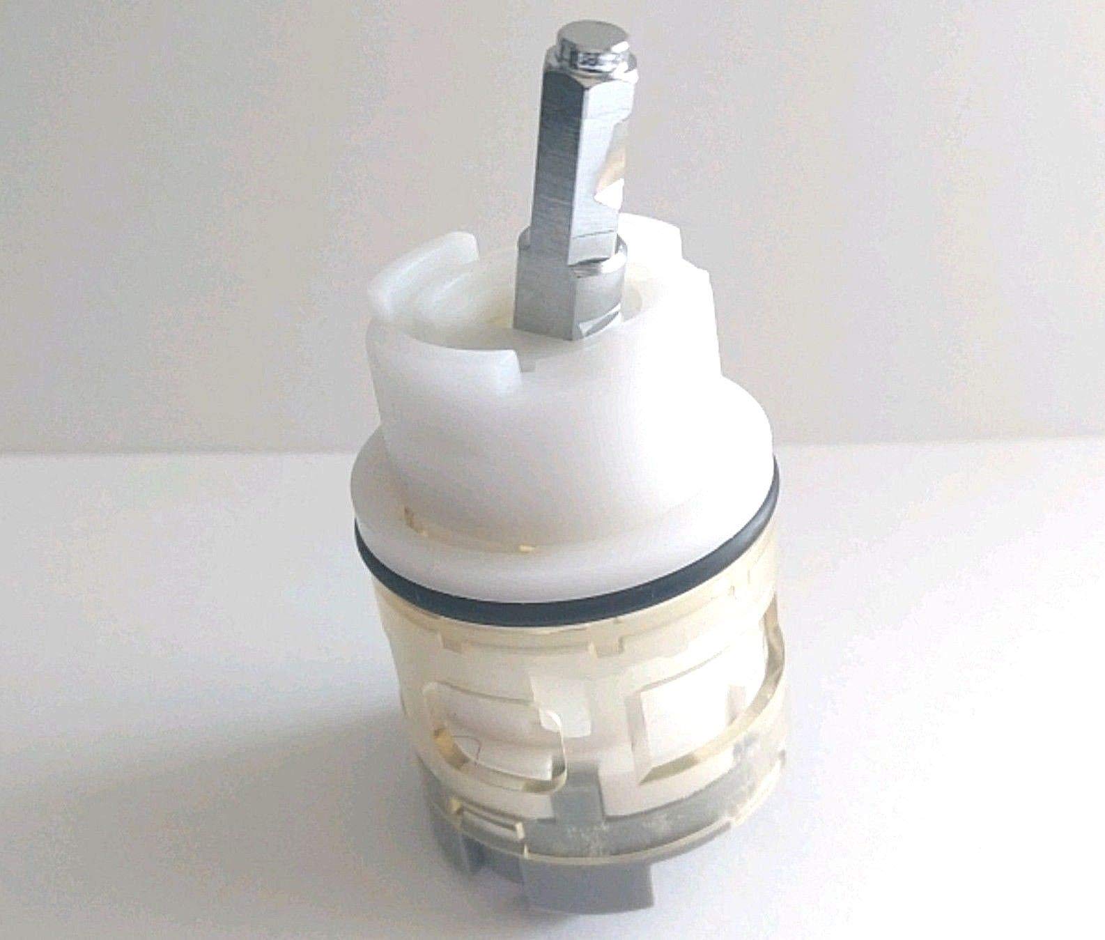 Cylindrical ceramic cartridge with metal stem and white plastic housing components stacked together.