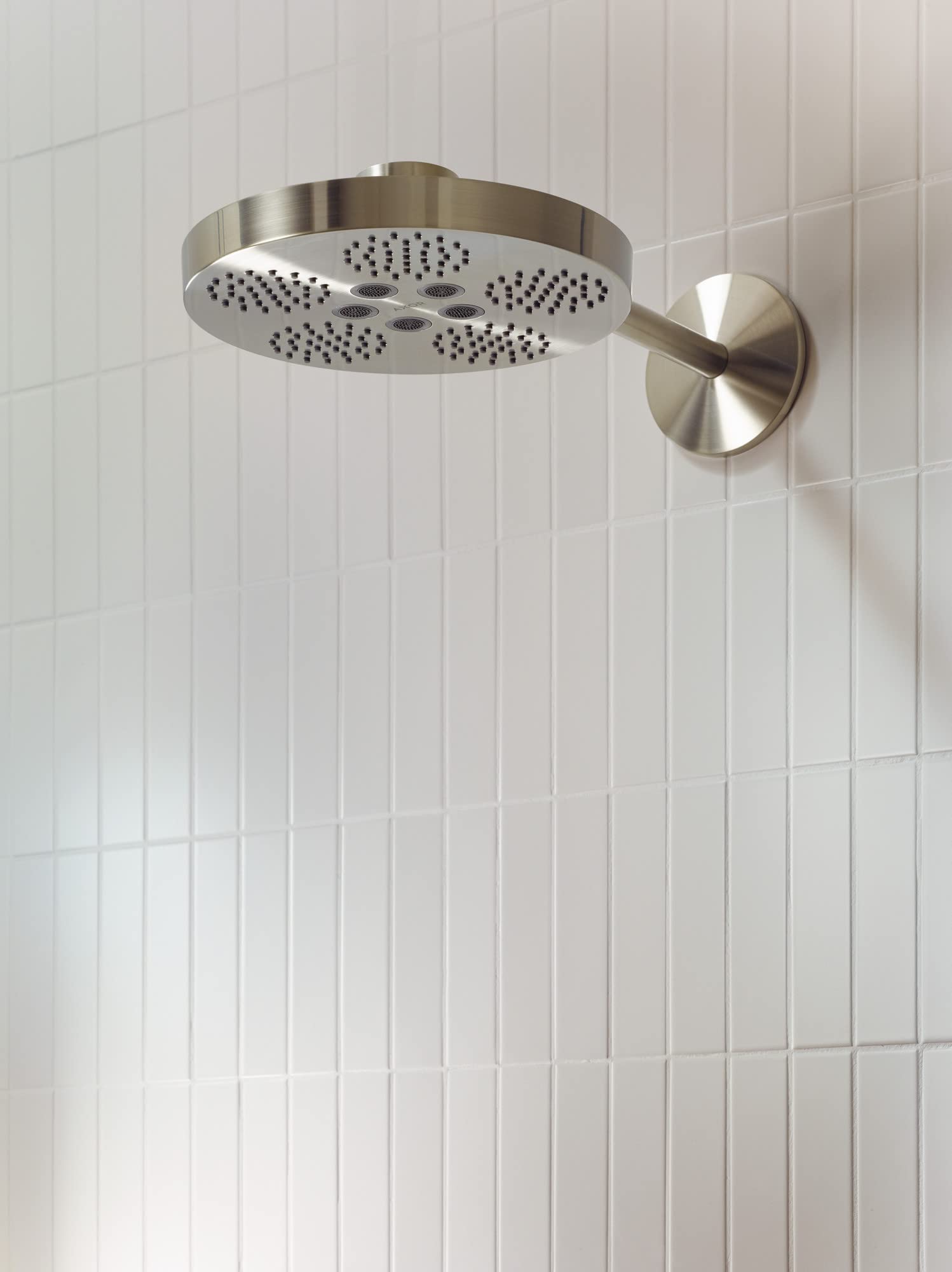 Brushed nickel round shower head with multiple spray jets mounted on white subway tile wall with attached arm.