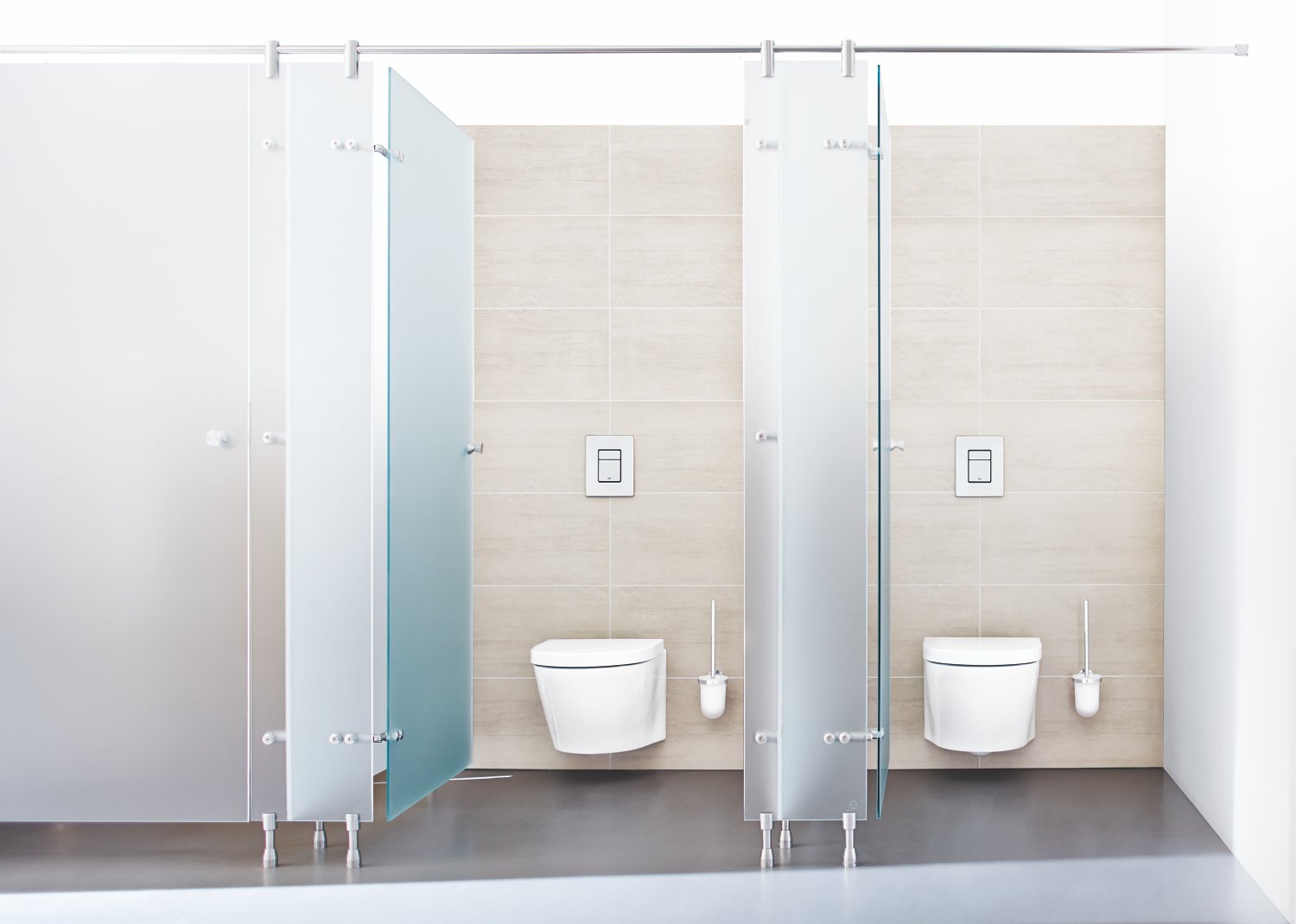 Brushed stainless steel rectangular wall plate mounted on beige tile behind toilet in bathroom stall.