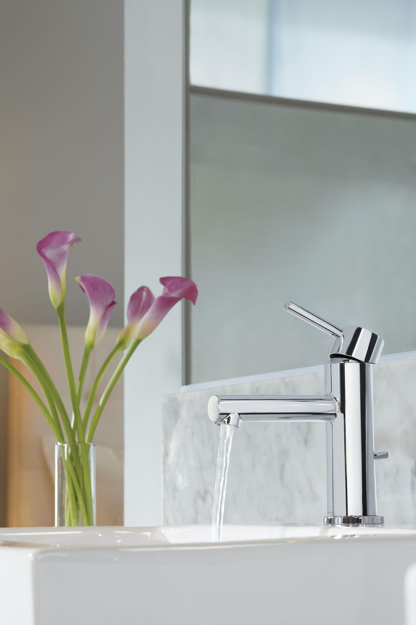 Chrome single-handle bathroom faucet with curved spout mounted on white marble sink with water running.