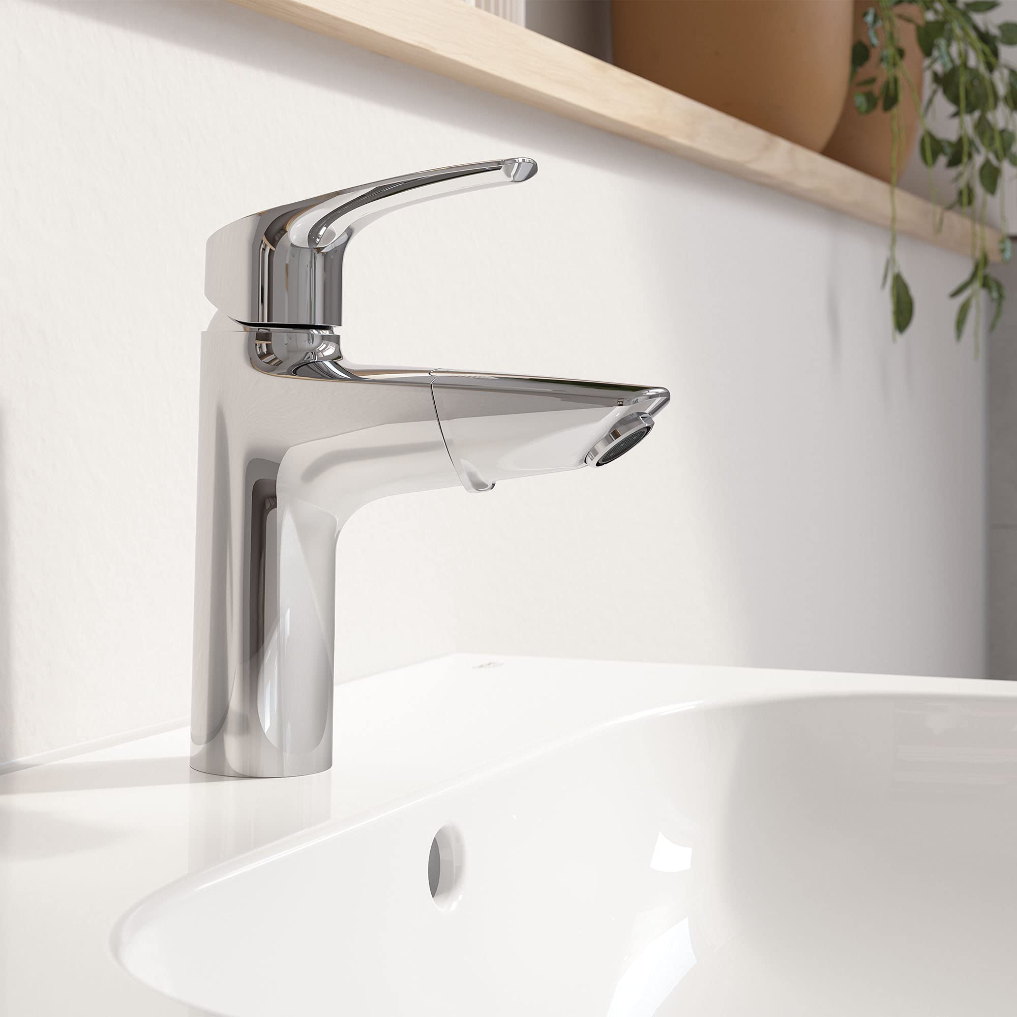 Chrome single-handle bathroom faucet with curved spout and pull-out spray head mounted on white sink.