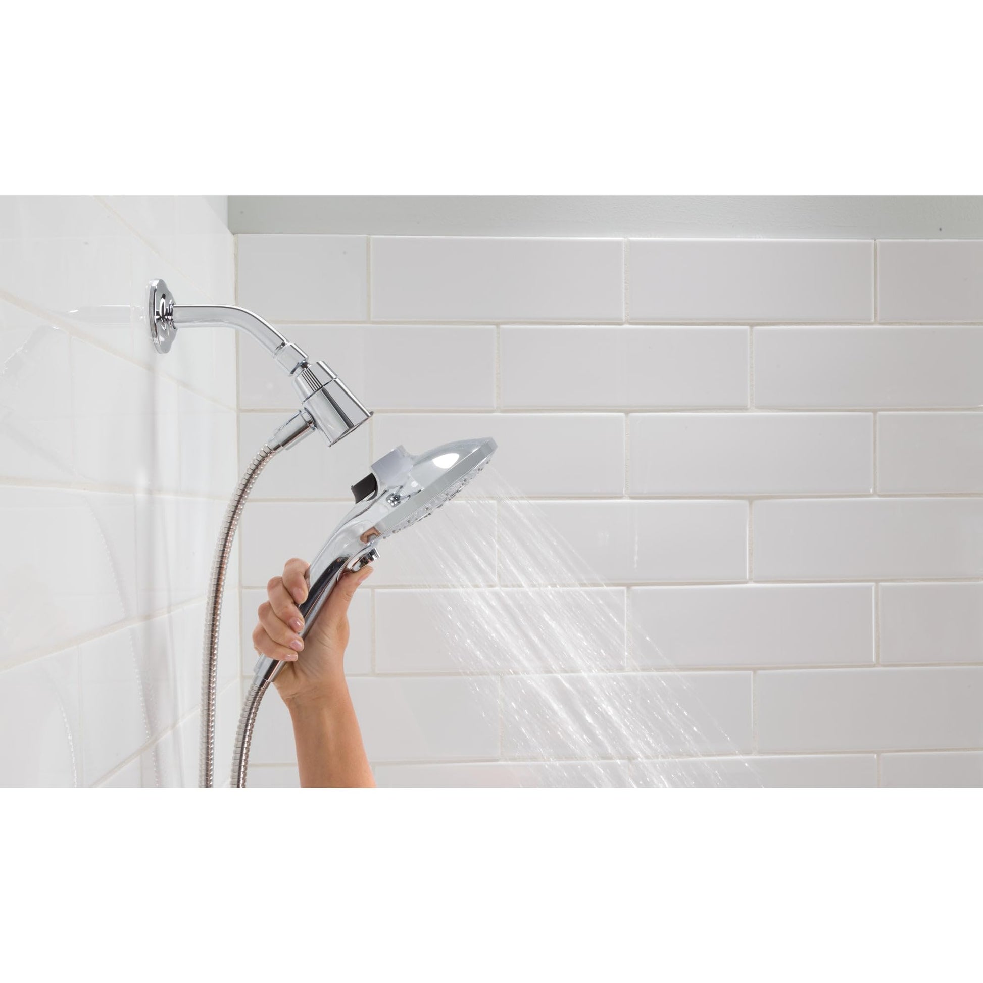 Brushed gold handheld showerhead with metal hose and wall-mounted docking system spraying water in shower.