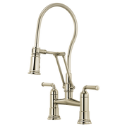 Polished nickel bridge faucet with flexible hose sprayer and dual handles on white background.