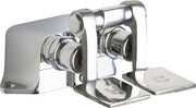 Chrome pedal valve faucet with two foot pedals and dual water outlets mounted on a flat base.
