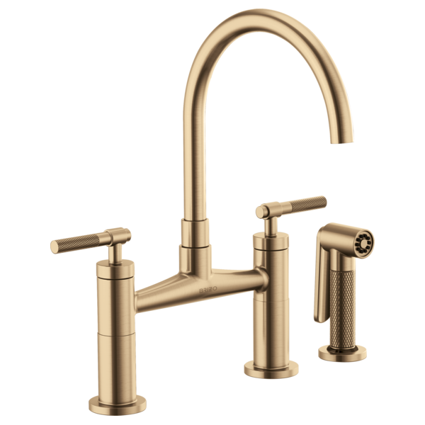 Champagne bronze bridge faucet with arched spout, dual knurled handles, and matching side spray.