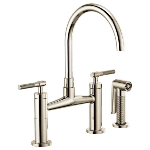 Polished nickel bridge faucet with high arc spout, two knurled lever handles, and separate sprayer attachment.